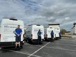 Photo of three Ford mobile service vans parked in lot with a technician standing at the back of each