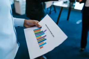Man's hand holding paper with bar chart on it