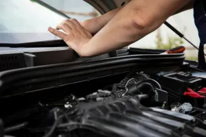 Photo of man's hands resting on a vehicle's exeterior dash with the hood open