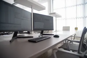 Two desktop computers side by side on otherwise empty office desk