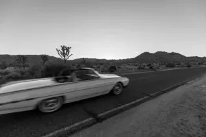 Vintage convertible driving along a desert highway, capturing the freedom and cultural impact of early American car travel.