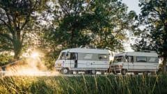 Two vans parked on road with scenic views behind.