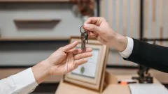 Two hands, one handing off set of keys to the other.