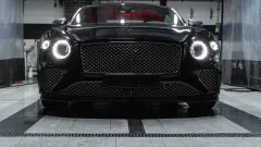 Front of black car with headlights on.