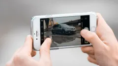 hands holding up a phone horizontally, zooming into a picture of a car