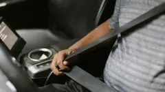 man buckling seatbelt in car with gray interior