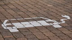 White drawing  on brick surface of car with a charger cable sticking out of it