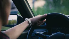 Man gripping vehicle steering wheel on a drive