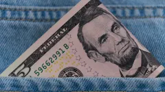 $5 bill poking out of blue jeans pocket
