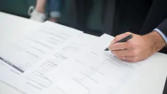 Man's hand holding pen over a paper document
