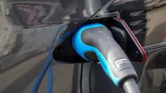 EV charger inserted into dark-colored car port
