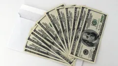 Fan of $100 bills atop a white envelope