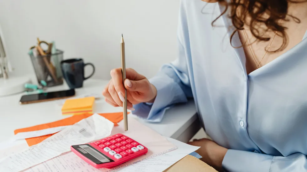 Photo of woman at desk using a calculator