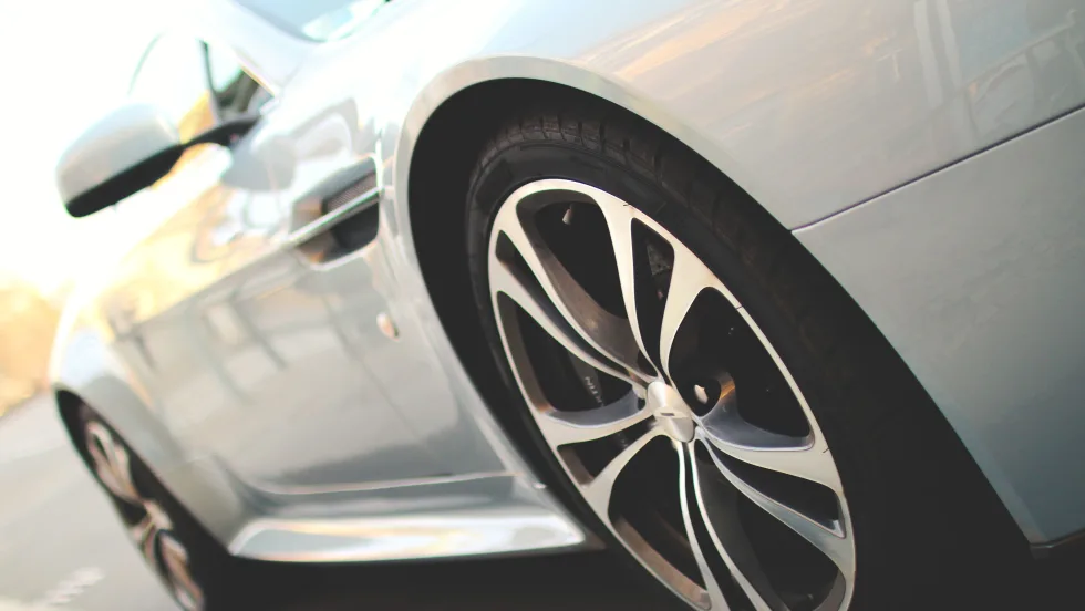 Closeup photo of a new white car on a road from the driver's side 