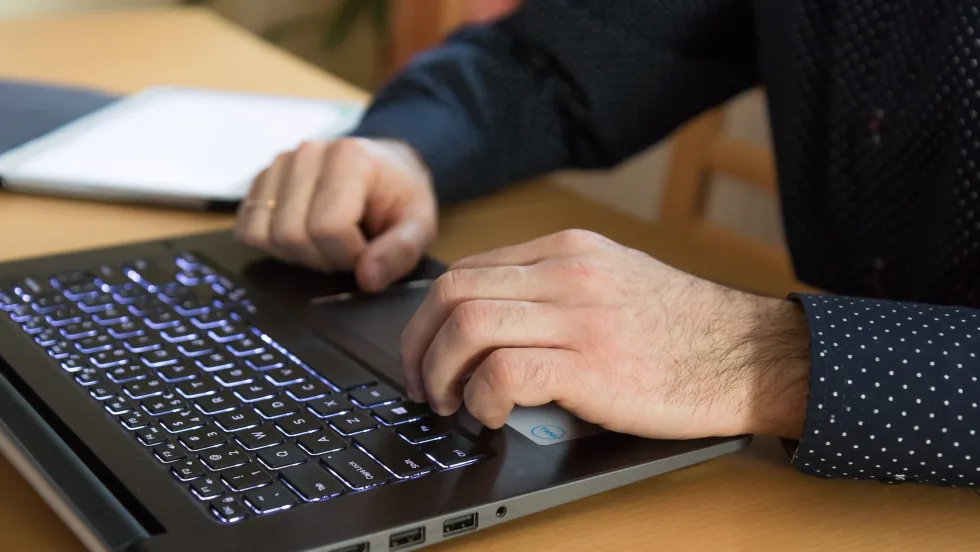 Photo of suited man's hands over a computer keyboard