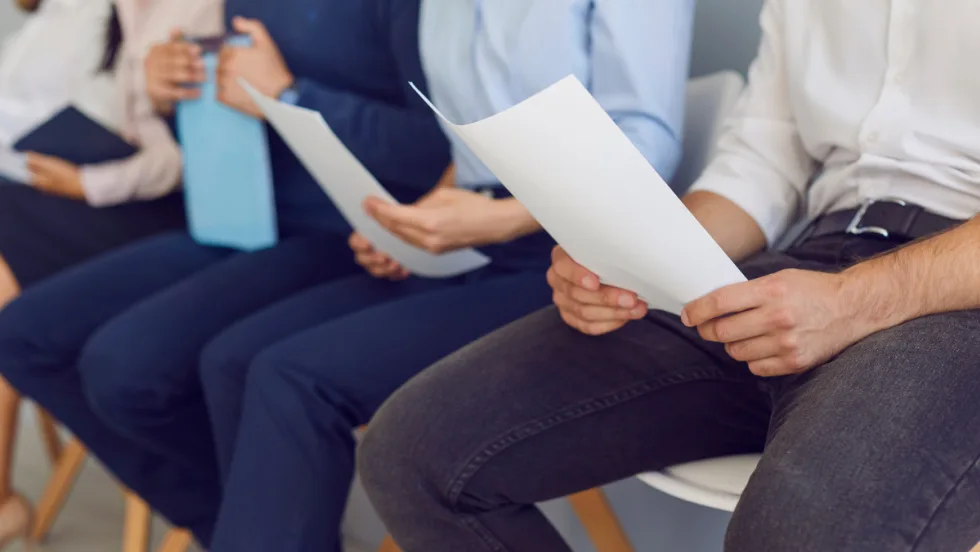 a line of people sitting down with paperwork in their hands