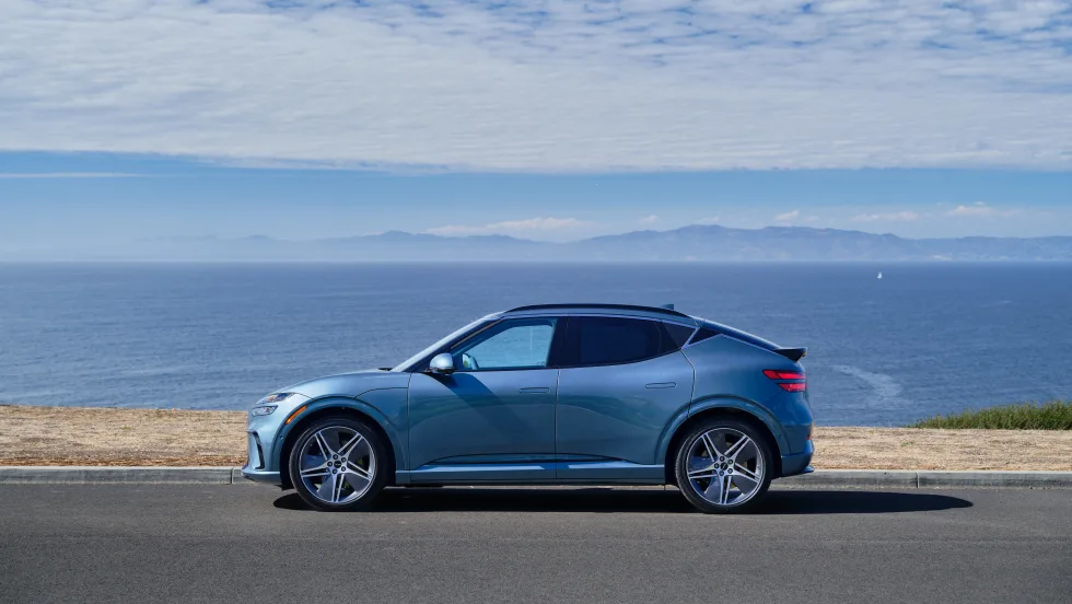 Blue Genesis car sitting in front of scenic mountainscape.
