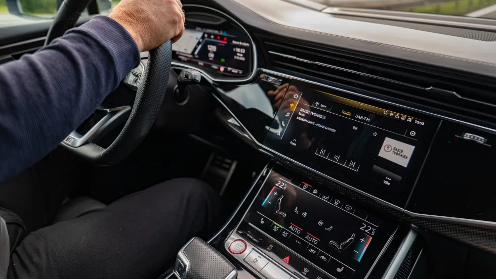 Interior of black car with persons hands on steering wheel.
