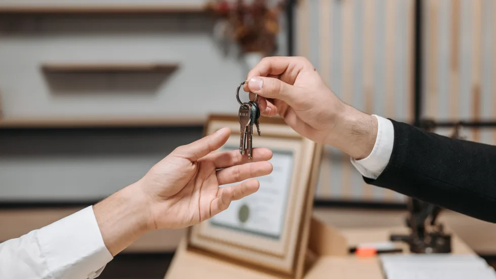 Two hands, one handing off set of keys to the other.