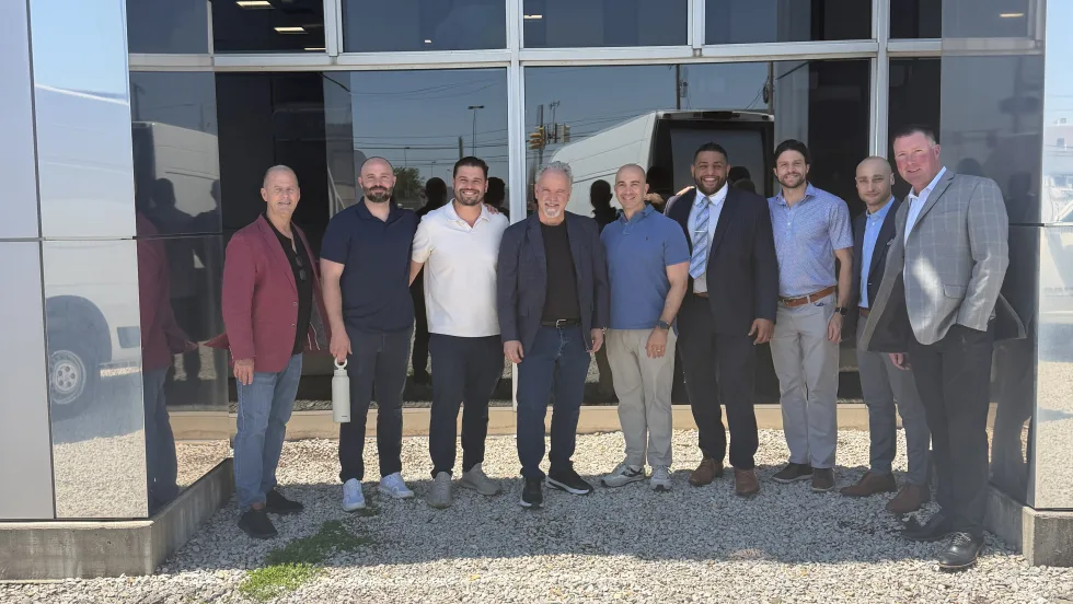 Group photo of men outside storefront.