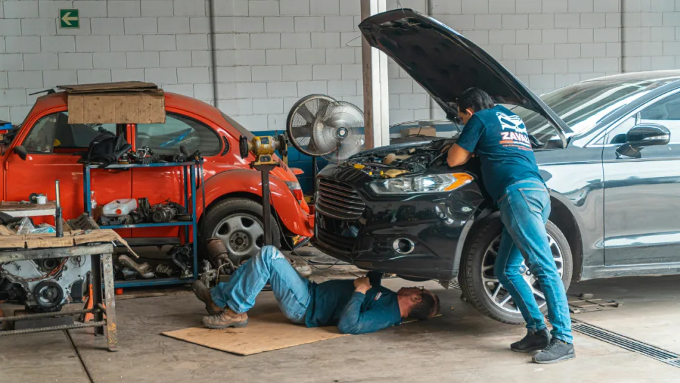 Two men do mechanical work on car.