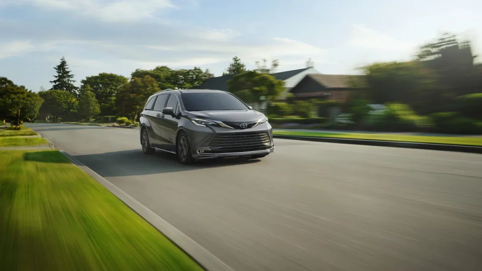 Toyota Sienna car driving down road.
