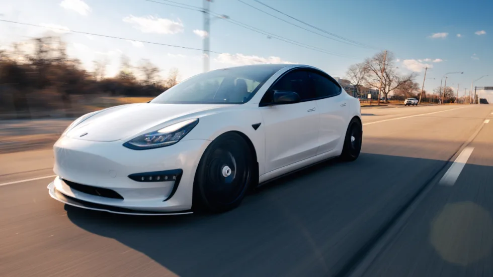 White Tesla car driving on road.