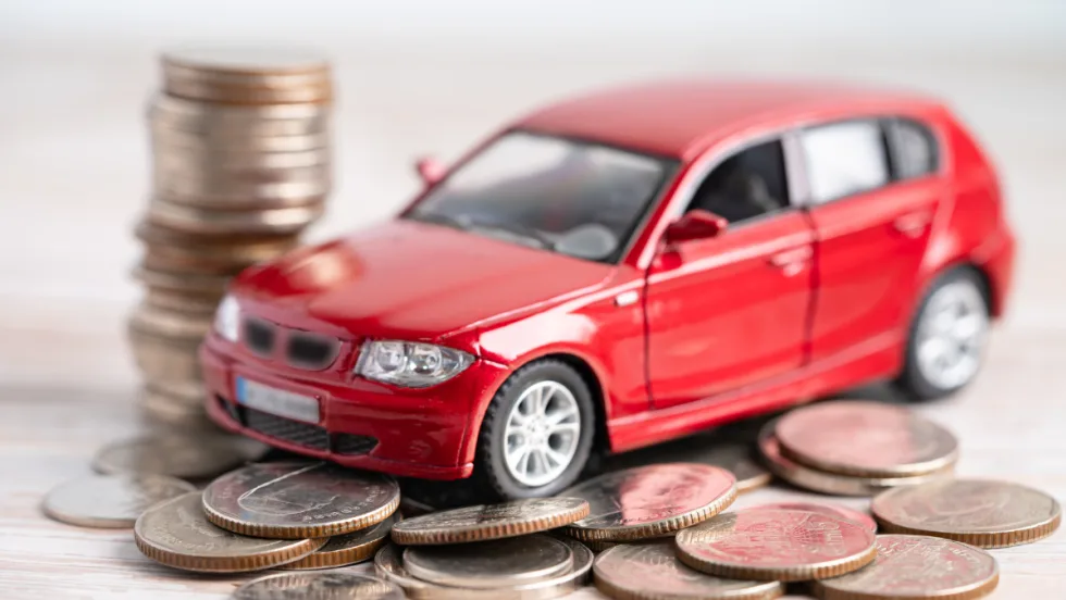 Red toy car sitting on top of coins.