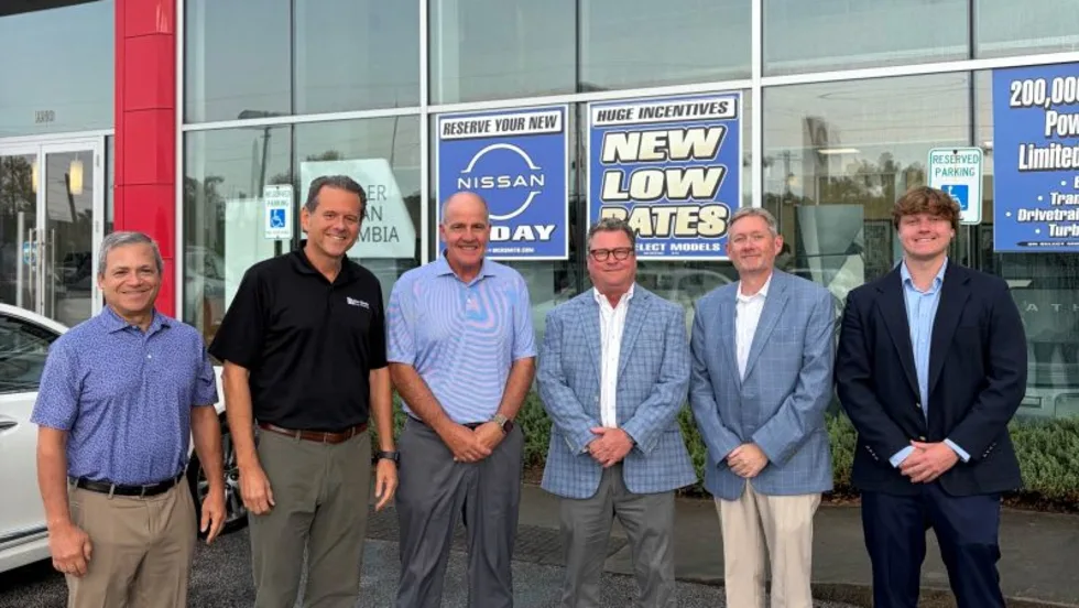Six men standing for photo outside of car dealership