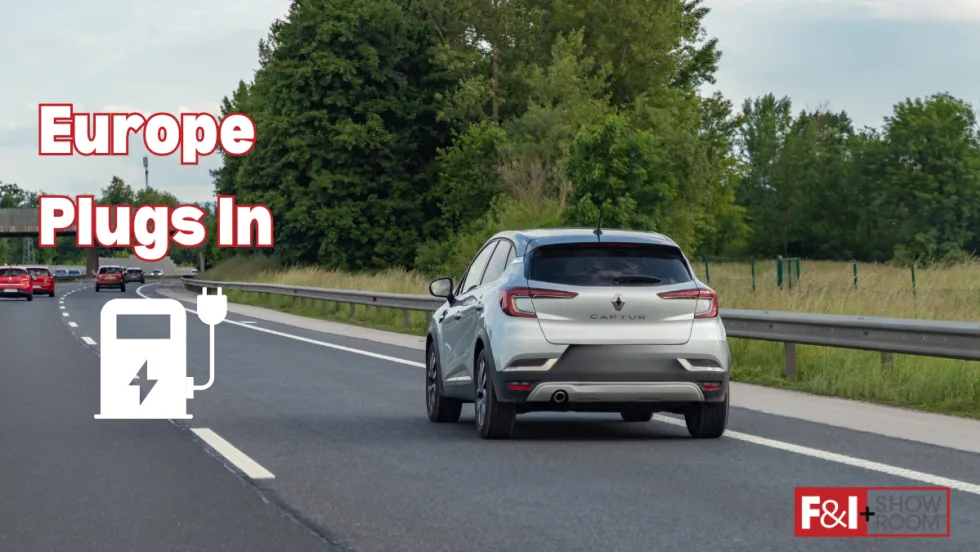 Silver car driving down road with graphic that says “Europe Plugs In”