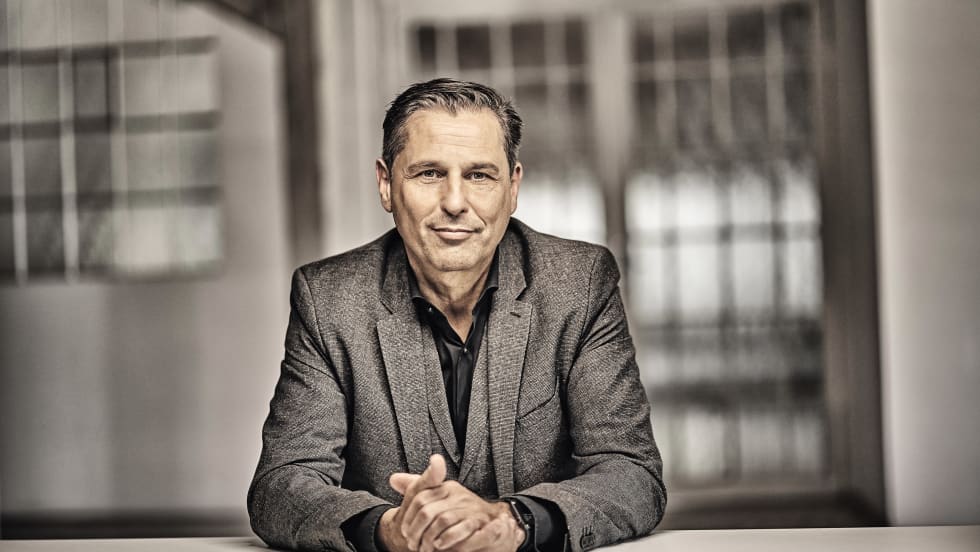 Smiling executive sitting at table with folded hands.
