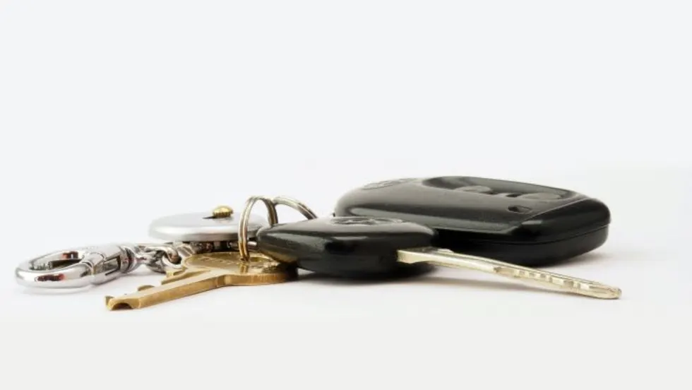 Photo of a keyring with mltiple keys, including a car key fob, on a white surface