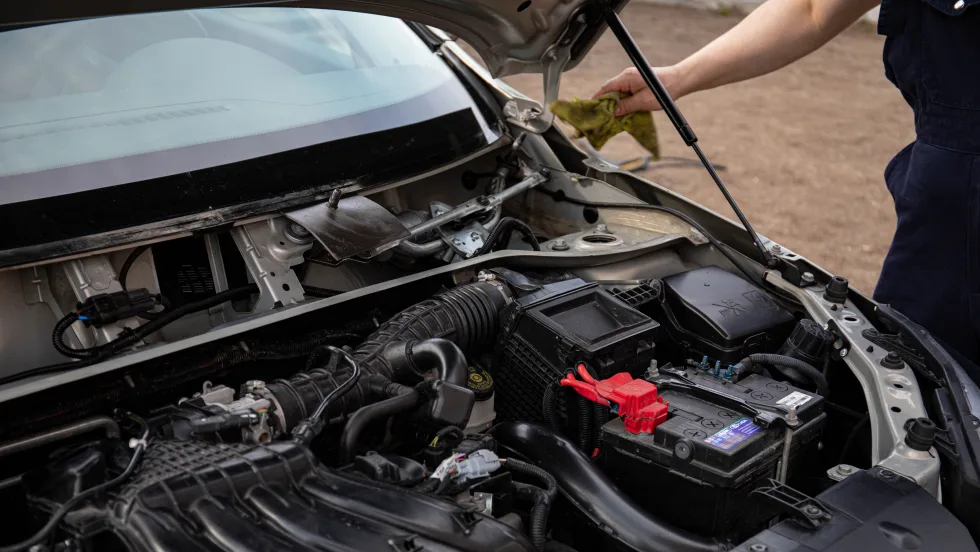 Arm of mechanice reaching for car with hood open