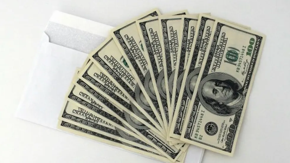 A fan of $100 bills sitting on a white envelope
