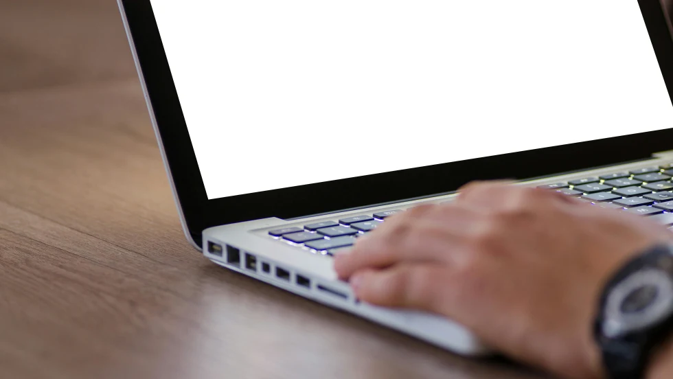 Photo of man's hand on laptop keyboard on a desk