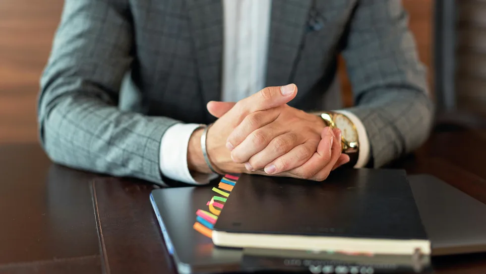 Photo of businessman's hands resting on files on a desk