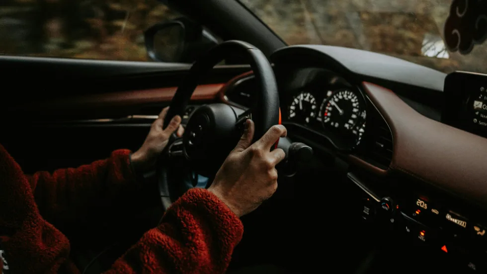 inside of car, view of steering wheel with hands on it driving
