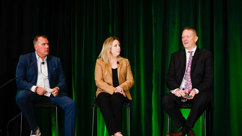 Two men and a woman on stage in discussion