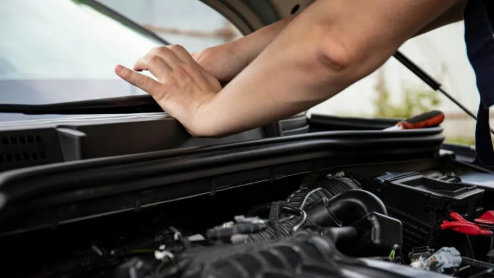 Photo of man's hands resting on a vehicle's exeterior dash with the hood open