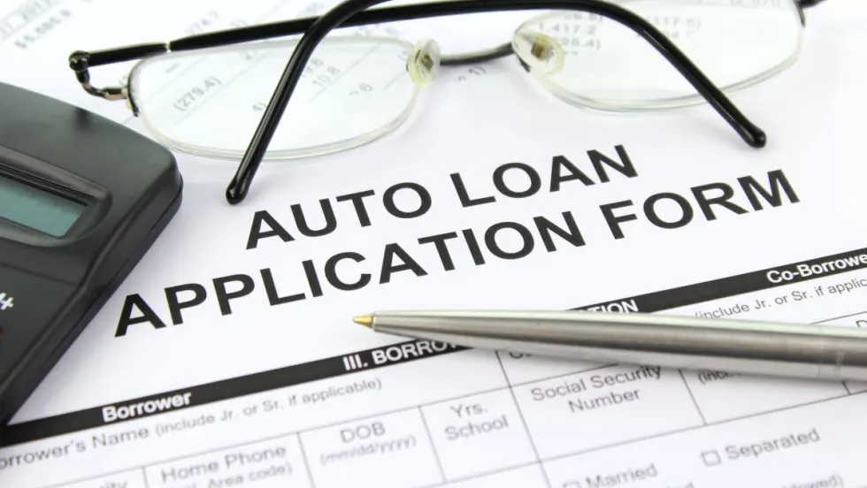 Photo of auto loan application form with eyeglasses, pen and calculator on top of it
