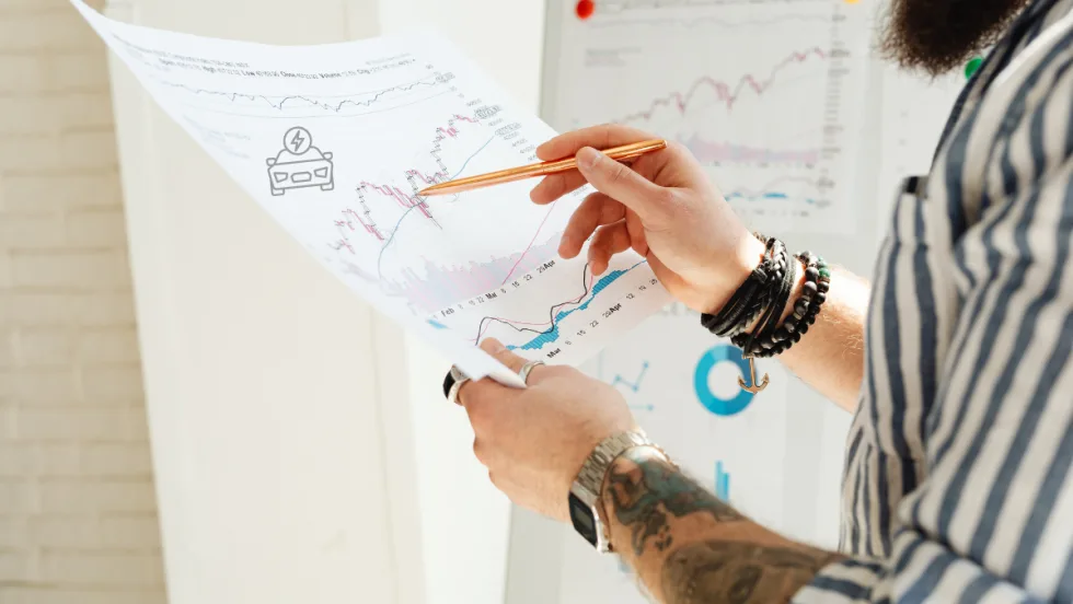 man holding up sales report and pointing with pencil