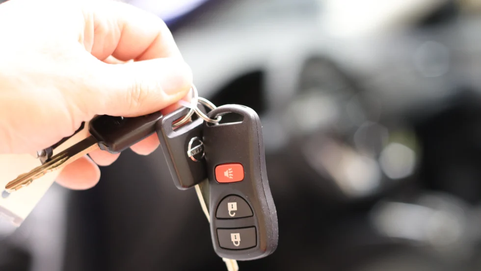 Man's hand holding a car key up for someone to take