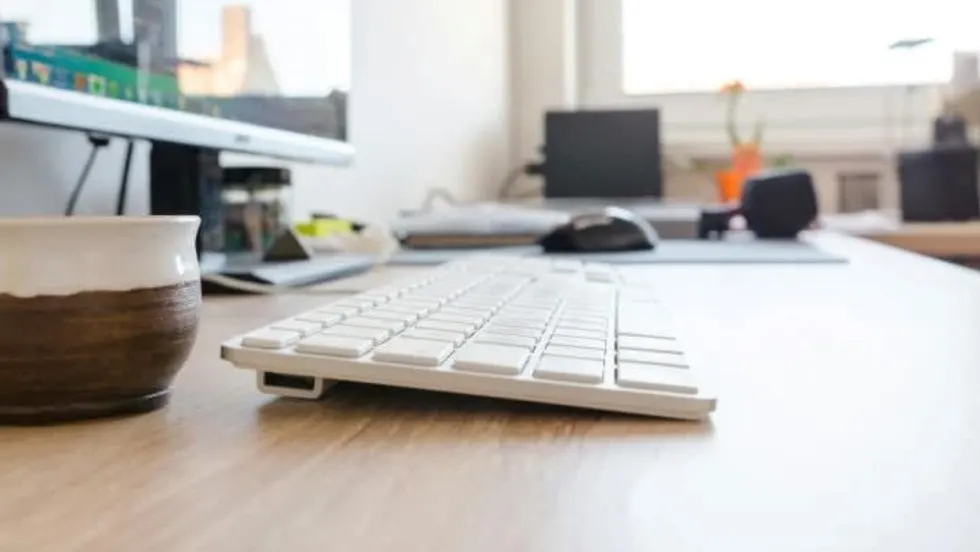 Image of a white keyboard on a wooden desk.