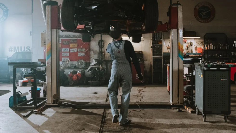 mechanic standing under lifted car in a garage