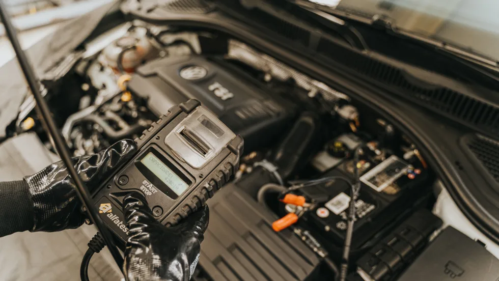 Mechanic holding digital device over an open vehicle engine