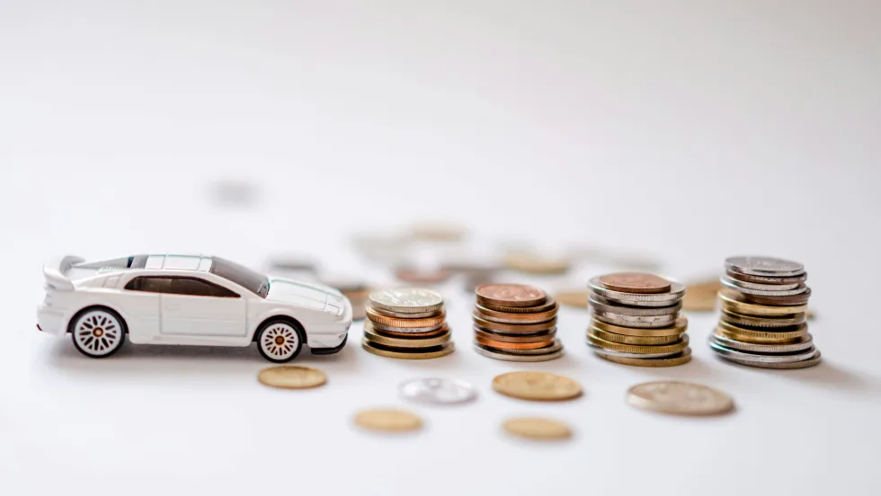 Photo of a white toy car next to piles of coins