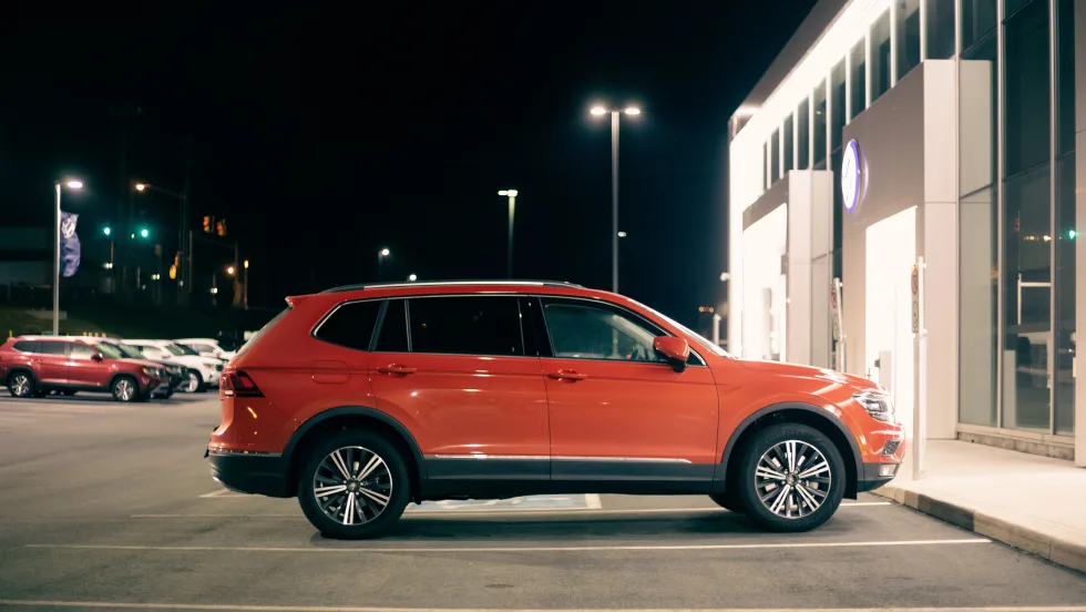 Photo of red SUV parked outside a car dealership after dark