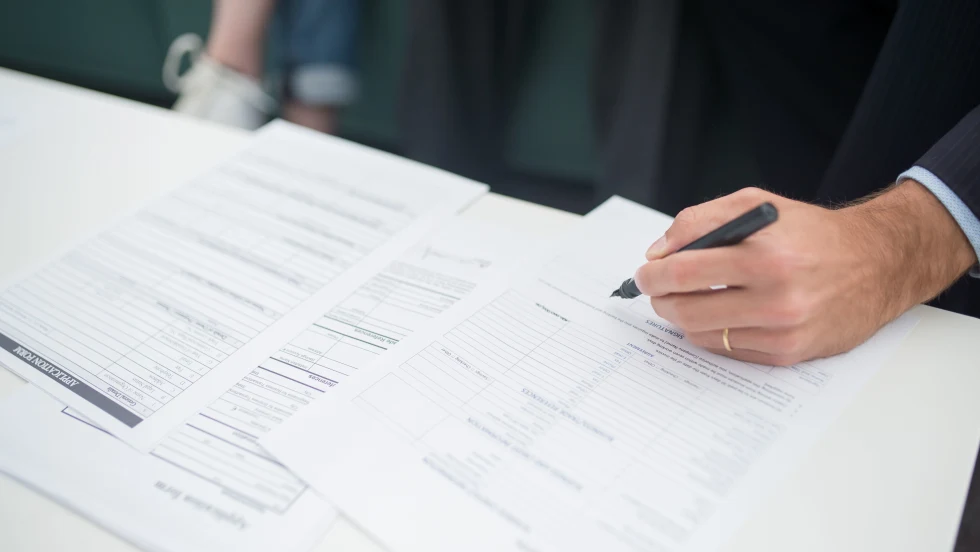 Man's hand holding pen over a paper document