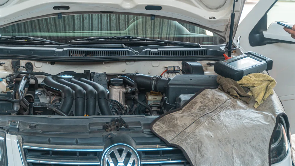 Open hood of a Volkswagen vehicle with a mechanic's rag draped over the front