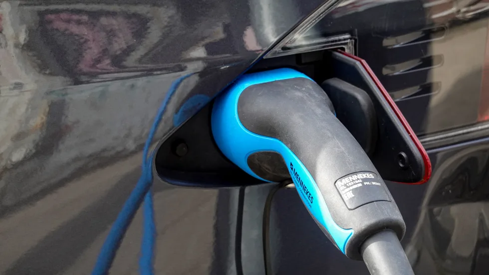 EV charger inserted into dark-colored car port
